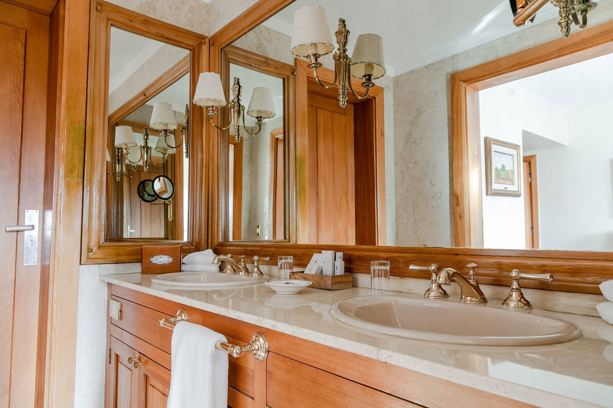 A bathroom with wooden cabinetry, two sinks, and a large mirror.