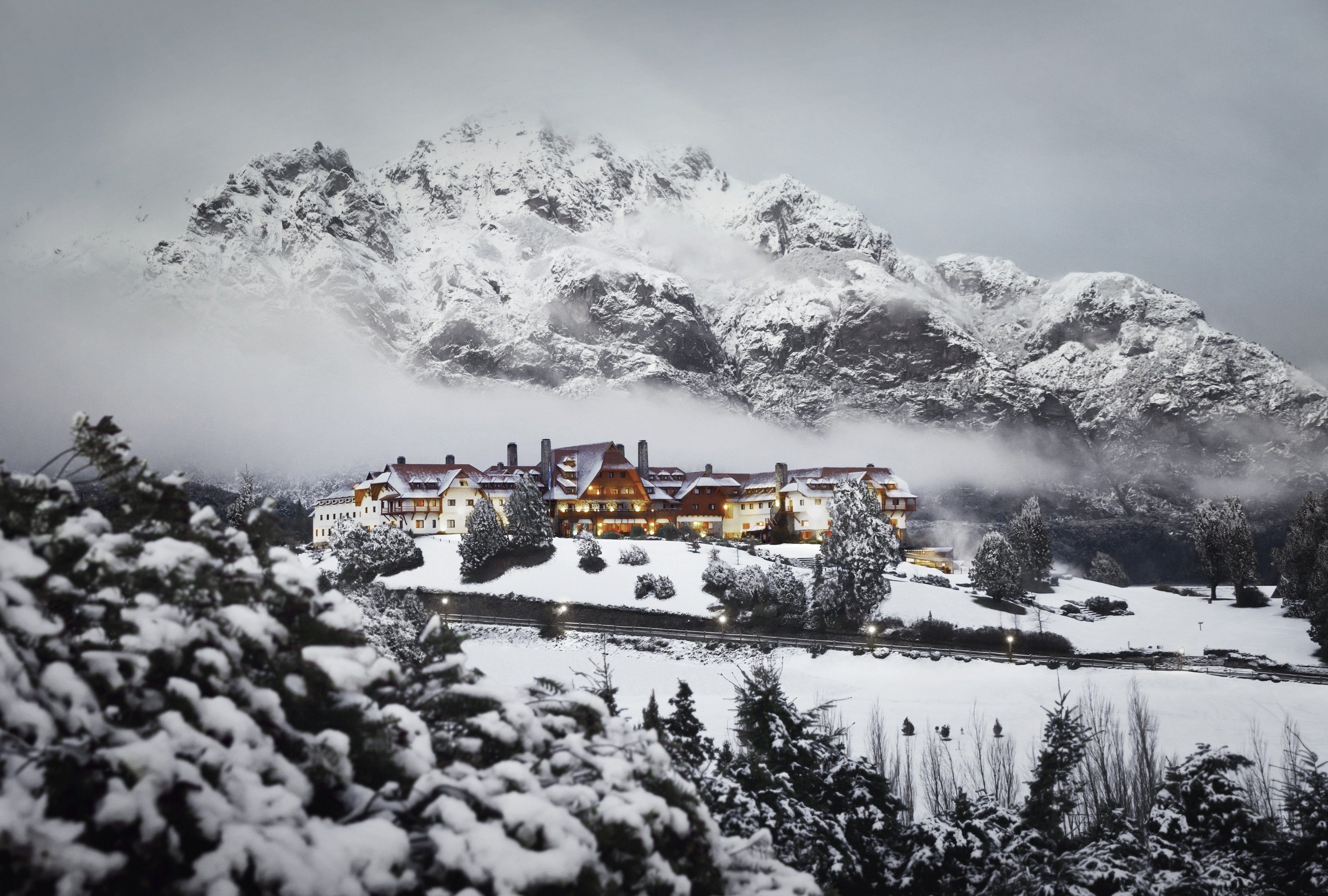 A snow-covered mountain with a large building in the foreground.