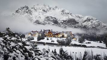 Una montaña nevada con un edificio grande al frente.