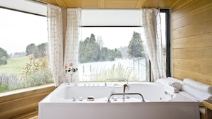 Un baño con bañera, lavamanos y ventana con cortinas.