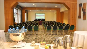 Ein Konferenzraum mit Reihen von Stühlen, einem Rednerpult und einer Leinwand im Vordergrund.