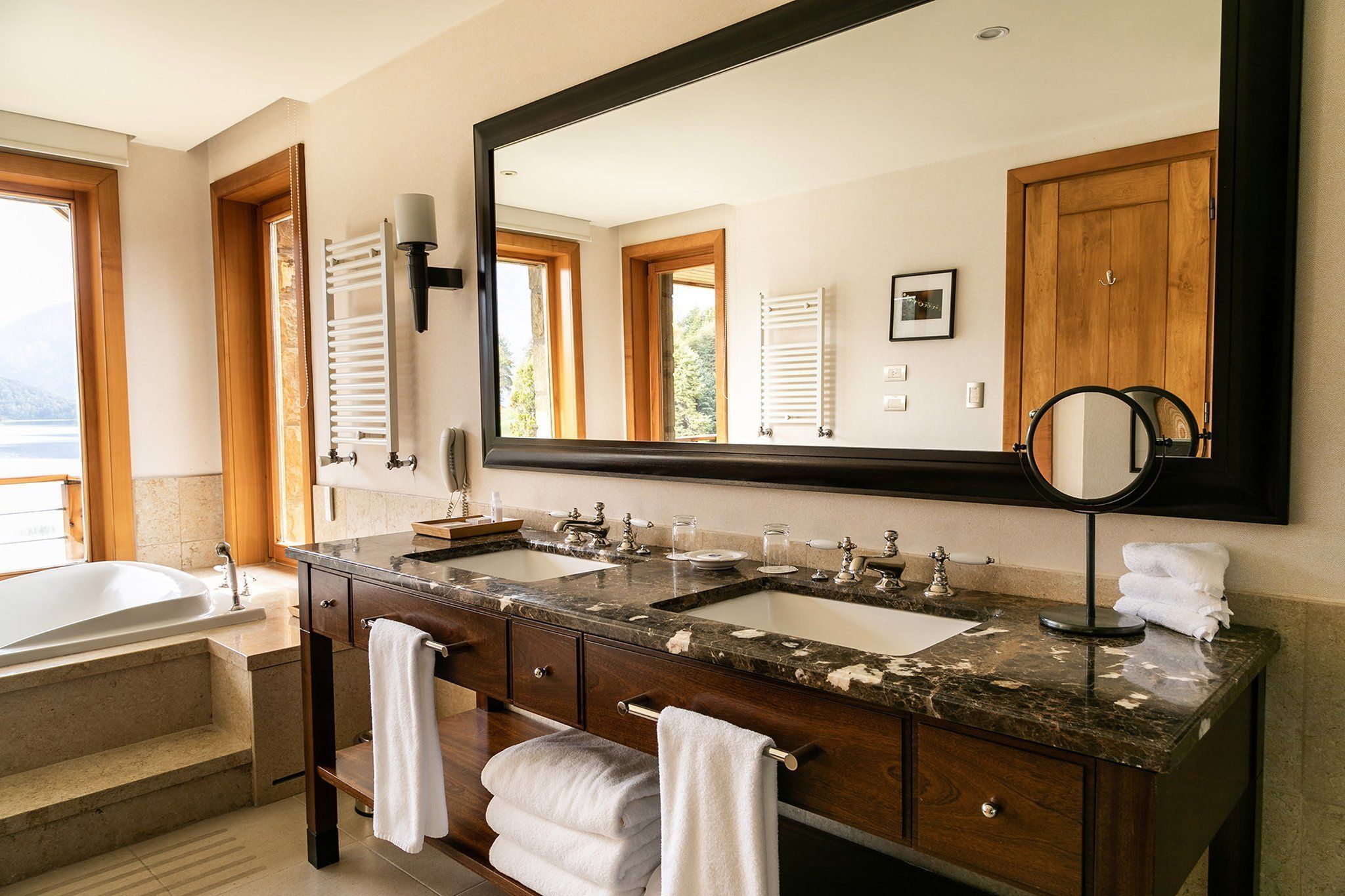 Une salle de bain avec un grand miroir, deux lavabos, une baignoire et des serviettes.