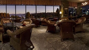Un rincón tranquilo con muebles de mimbre, suelo de piedra y amplias ventanas con vistas panorámicas.
