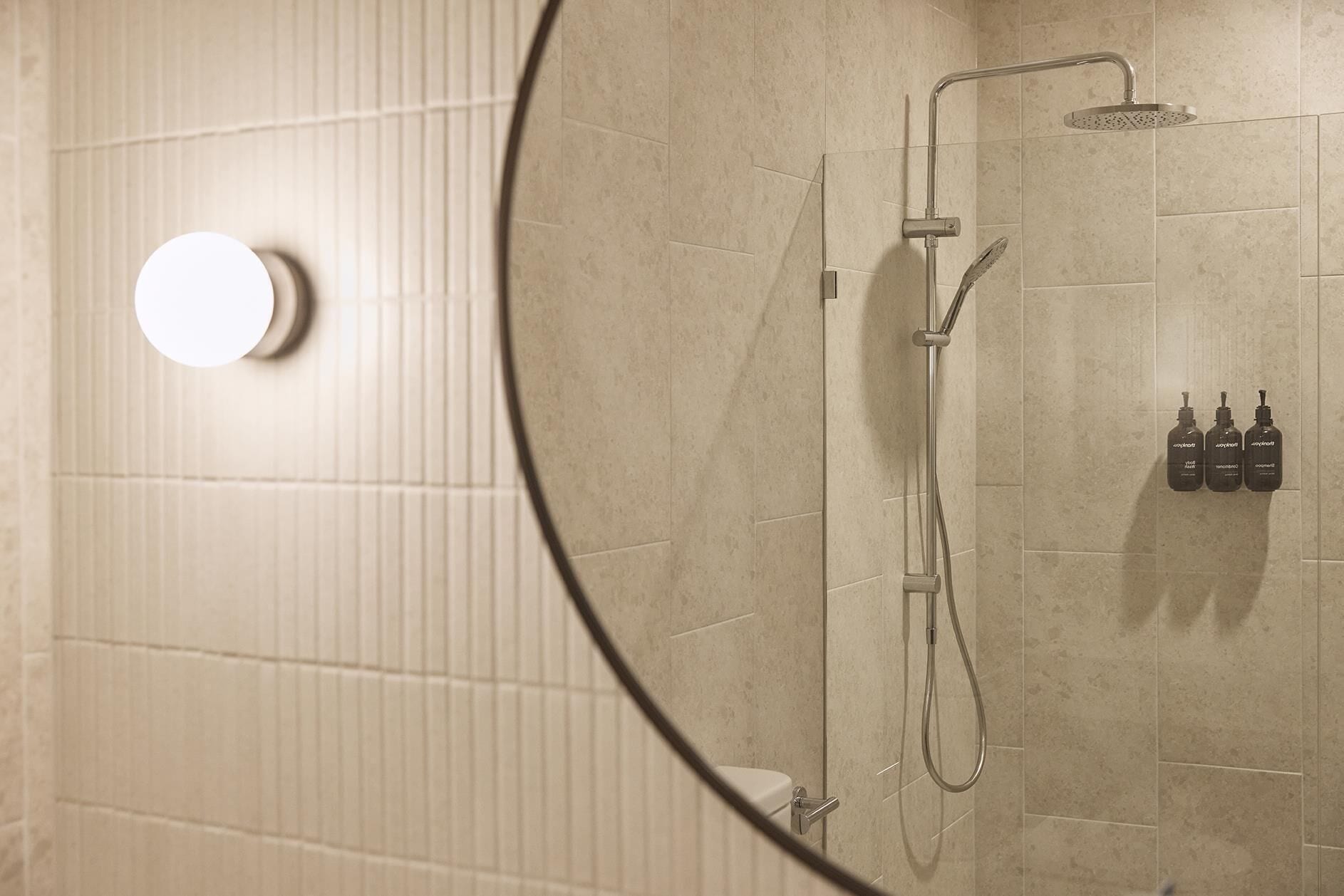 A bathroom with a shower, a toilet, and a mirror.