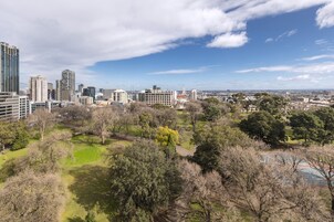 Un paisaje urbano con modernos rascacielos, un parque con árboles y un cielo despejado.