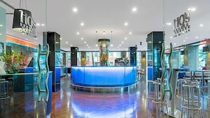 A modern hotel lobby with a central reception desk, bar area, and seating. - Flagstaff Gardens Hotel Melbourne (Melbourne)