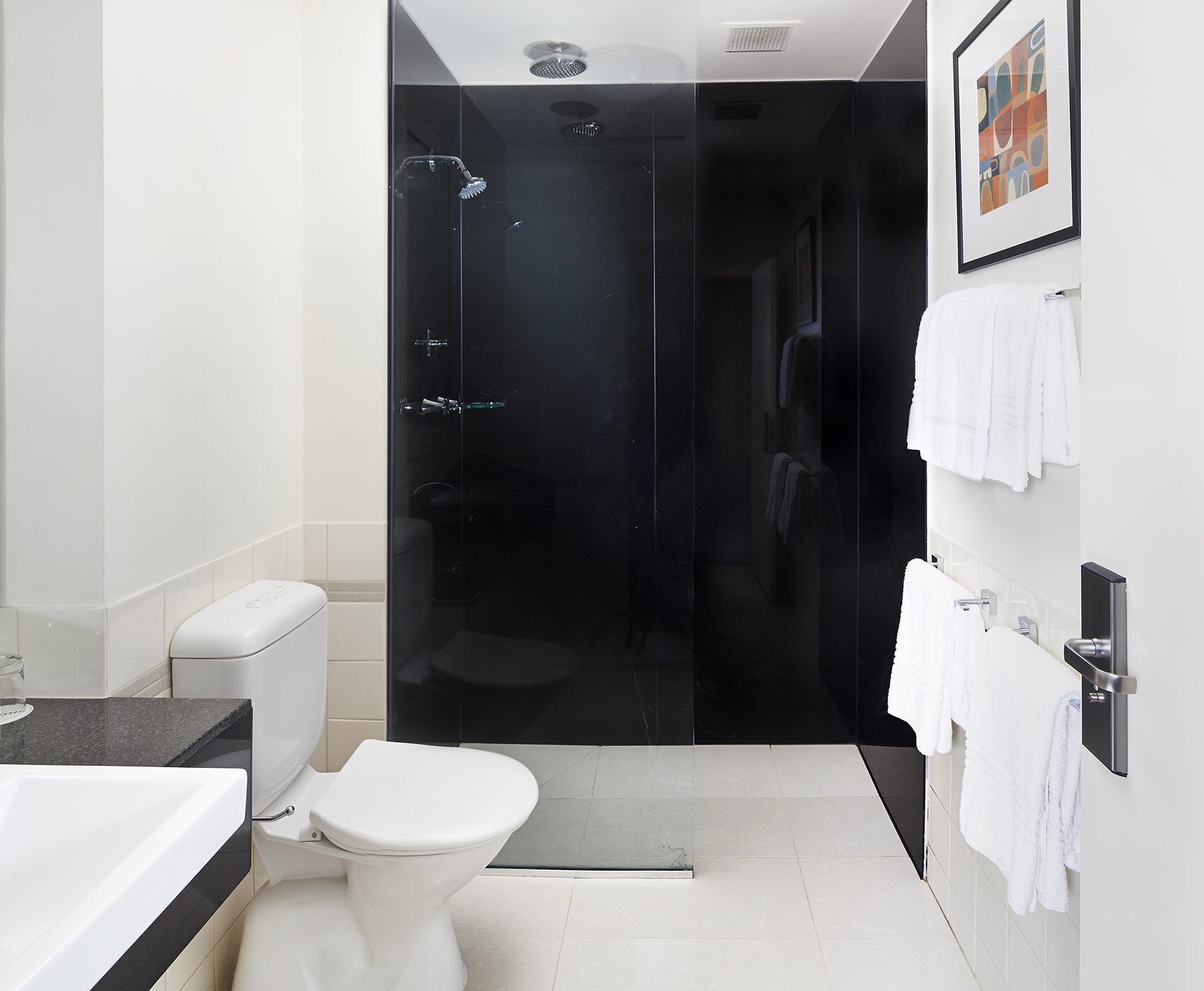 A modern bathroom with a glass-enclosed shower, a toilet, and a sink.