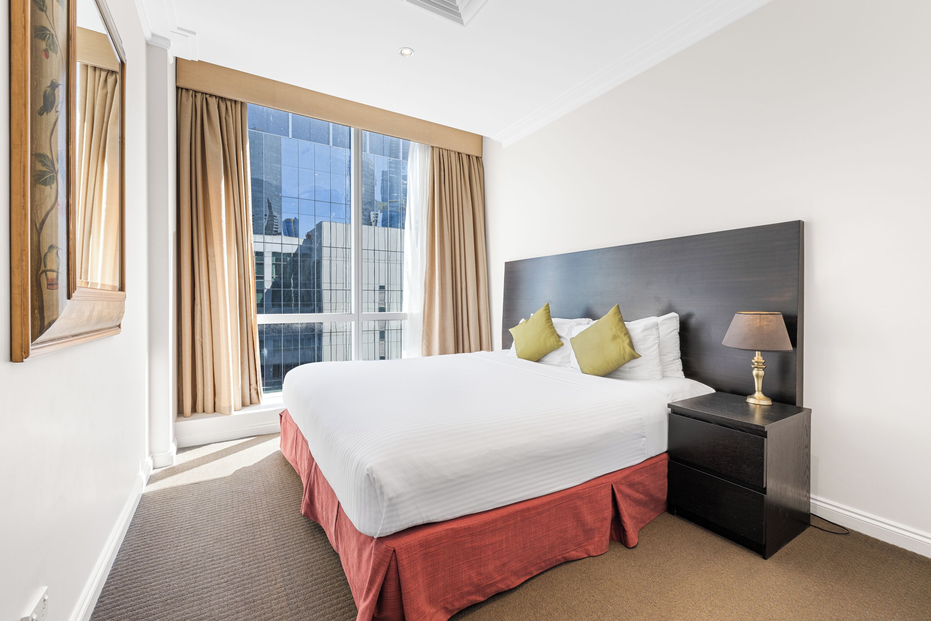 A hotel room with a large bed, a nightstand, and a window with curtains.