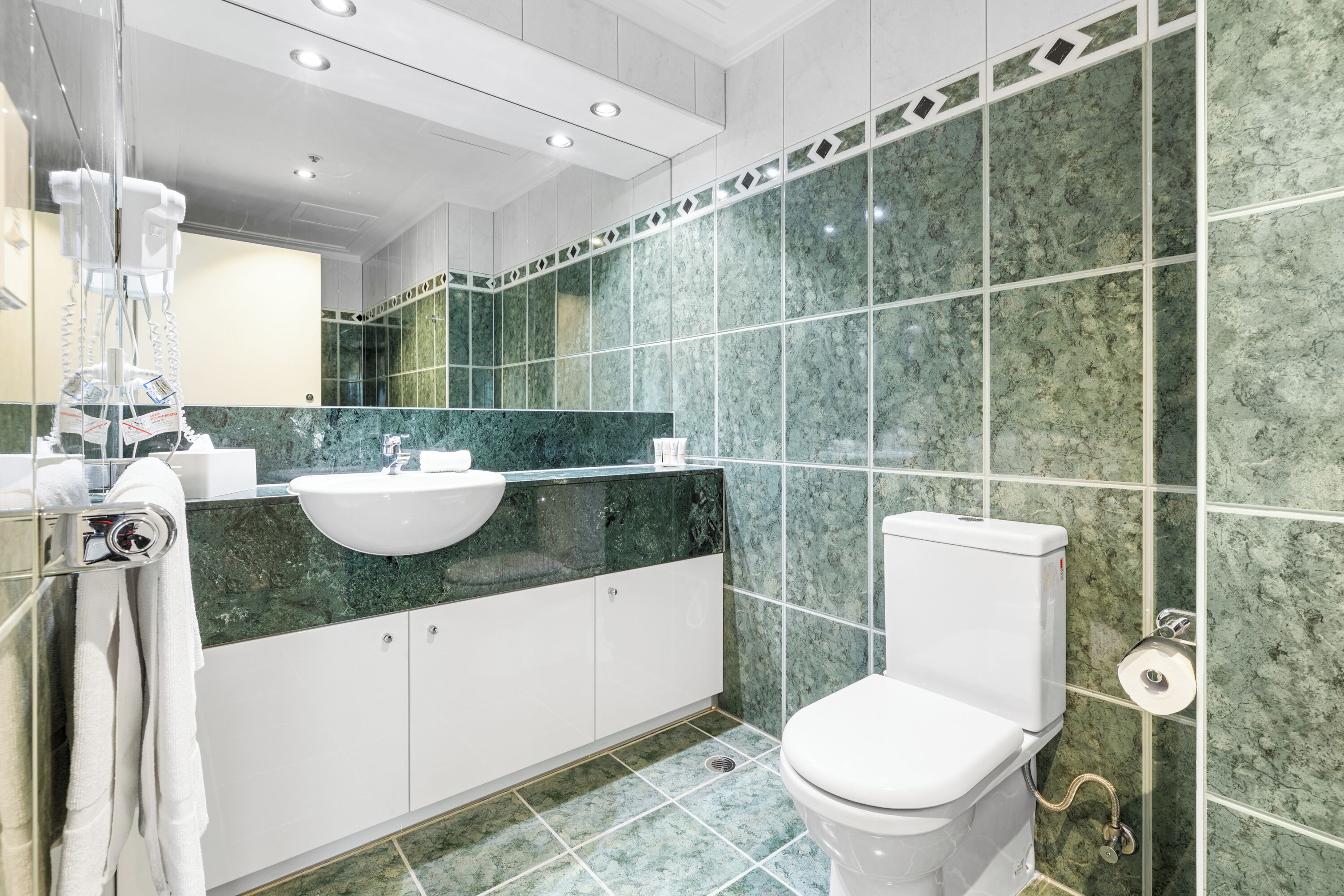 A modern bathroom with a white sink, a toilet, and a mirror.