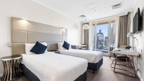 Une chambre d’hôtel avec deux lits, un bureau, une chaise, une télévision et une vue sur la ville.
