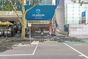 A hotel entrance with a blue awning labeled 'Clarion Suites Gateway,' a parking sign, and a flag. - Clarion Suites Gateway (Melbourne)