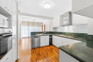Una cocina moderna con armarios blancos, una campana extractora de acero inoxidable, un microondas integrado y una encimera de granito.