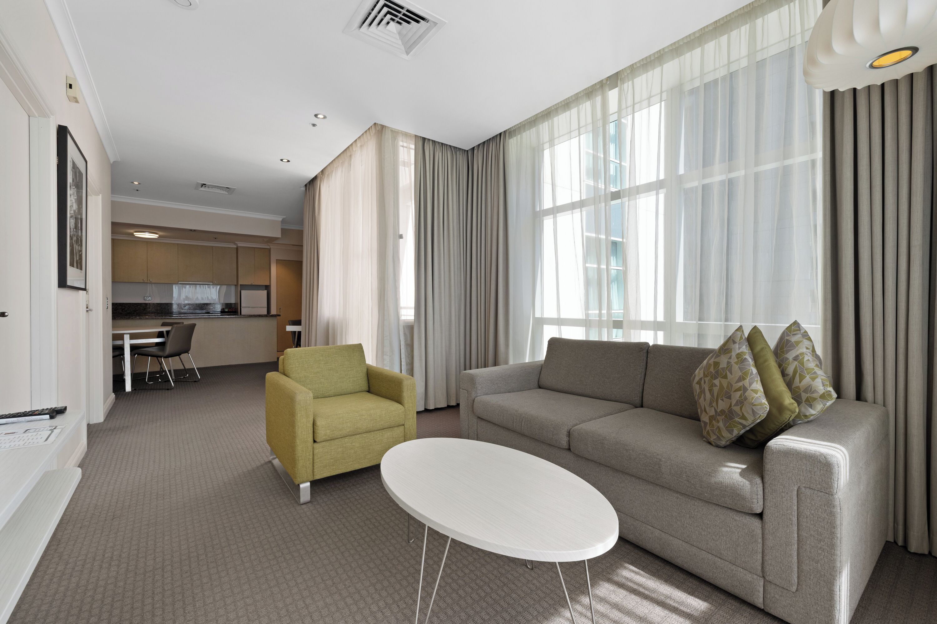 A modern living room with a sofa, armchair, and a small white table.