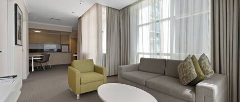 A modern living room with a sofa, armchair, and a small white table.