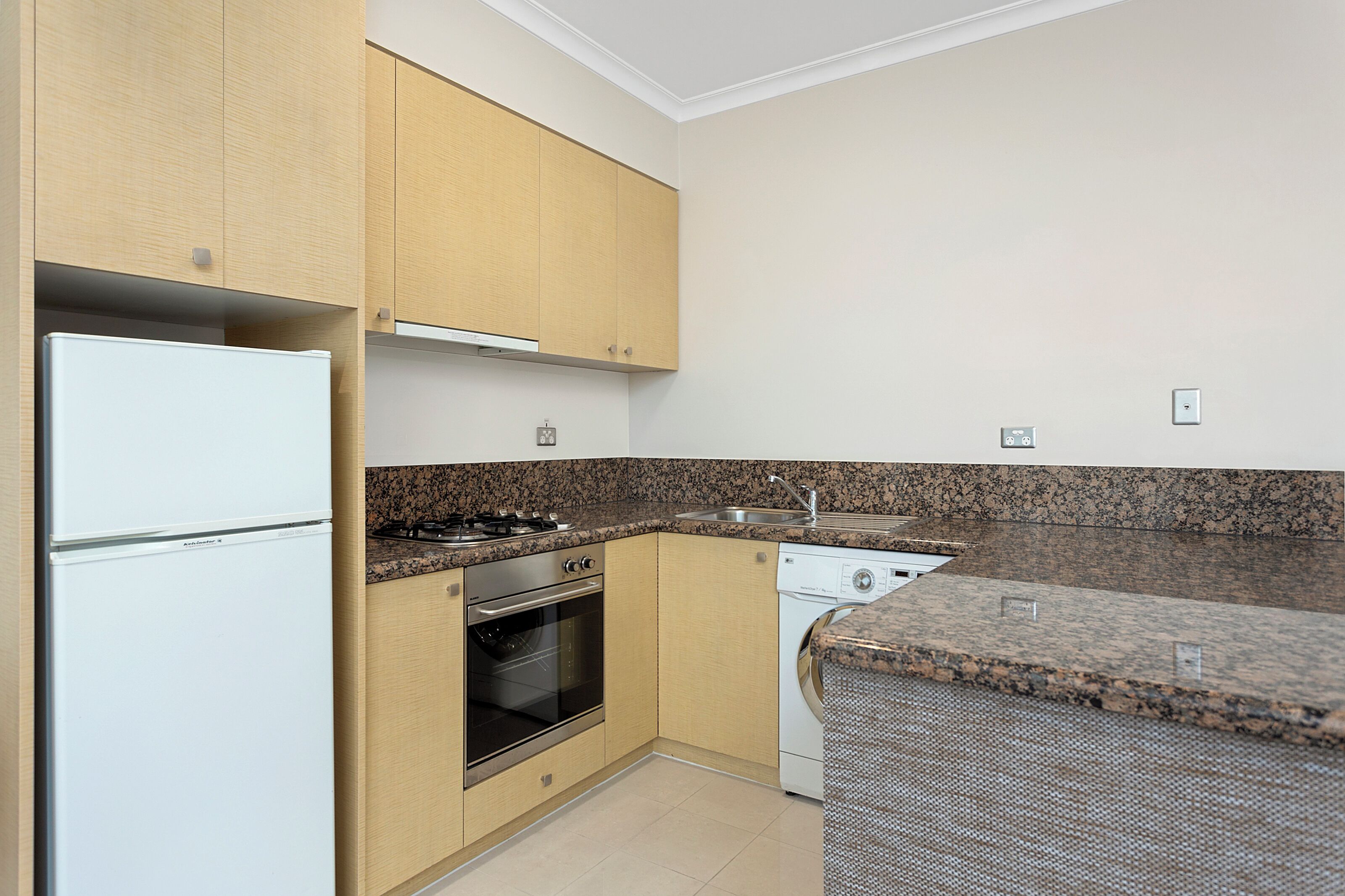 A kitchen with wooden cabinets, a white refrigerator, a stove, an oven, and a dishwasher.