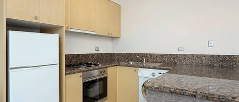 A kitchen with wooden cabinets, a white refrigerator, a stove, an oven, and a dishwasher.