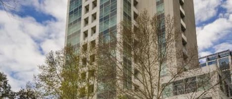 Un edificio alto y moderno con fachada de vidrio y una entrada visible en la base.
