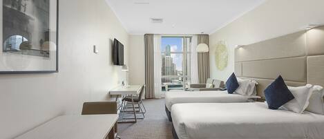 A hotel room with two beds, a desk, and a chair.