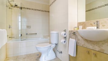 Un baño moderno con cabina de ducha de vidrio, inodoro blanco y lavamanos con encimera de mármol.