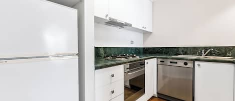 A modern kitchen with white cabinetry, a stainless steel stove, and a dishwasher.