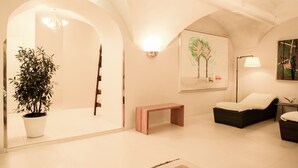 A modern living room with a potted plant, a bench, a sofa, and a painting on the wall. - Schlossberghotel (Graz)