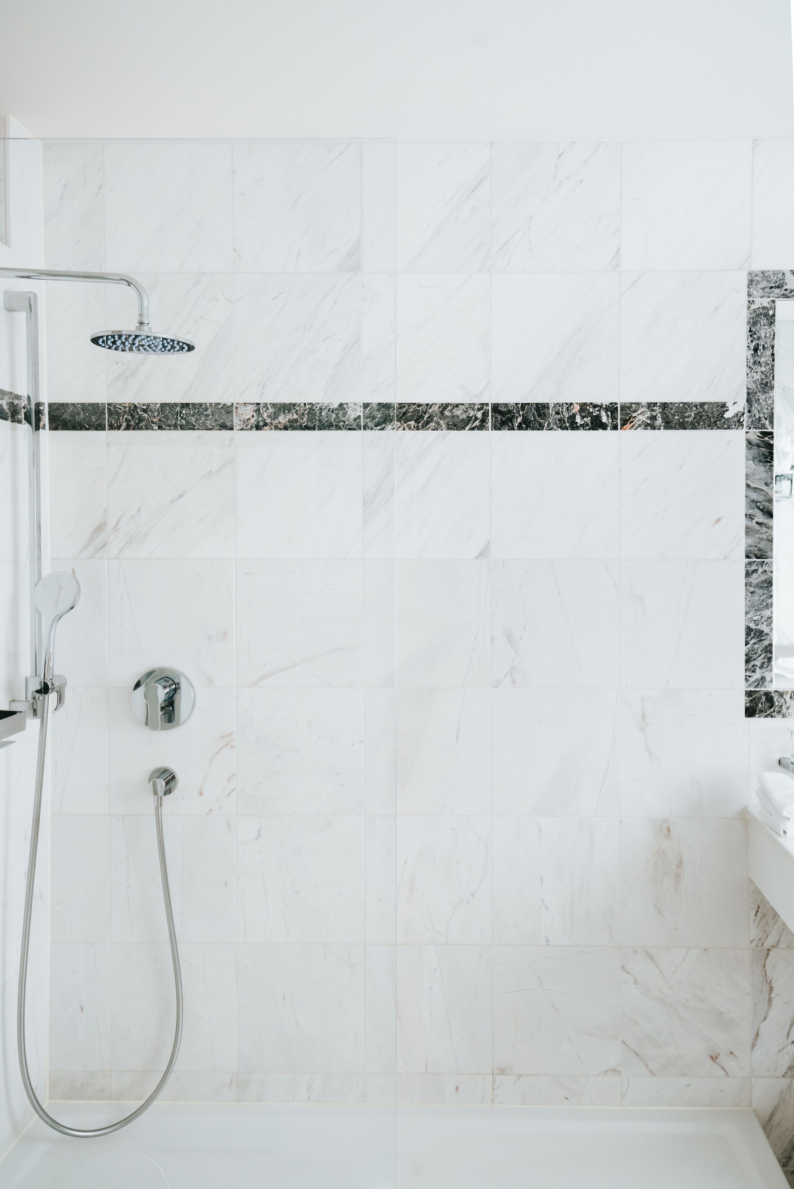A shower area with a glass door, a handheld showerhead, and a wall-mounted control panel.