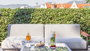 A seating area with a table, two glasses of drink, and a bowl of snacks. - Schlossberghotel (Graz)