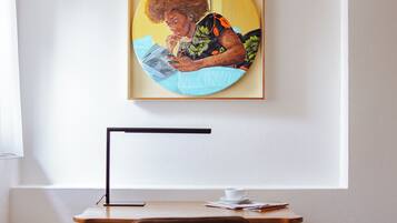 Ein Zimmer mit Schreibtisch, Stuhl und einem gerahmten Kunstwerk an der Wand.