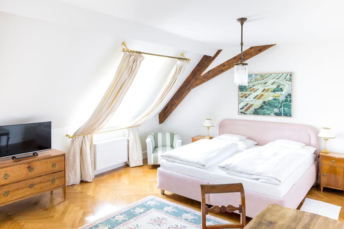 Ein Schlafzimmer mit Bett, Fernseher, einem Holzschrank, Stuhl, Tisch und einem Bild an der Wand.