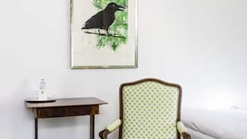 Ein Zimmer mit einem Holztisch, einem Stuhl mit grün gepunkteter Polsterung und einem Bilderrahmen mit einem Vogelbild an der Wand.