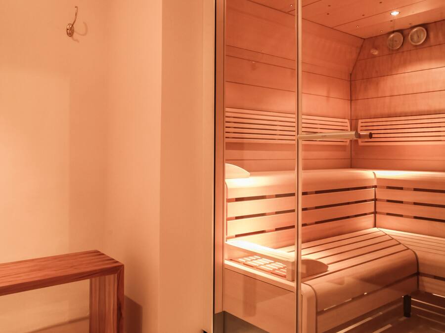 A sauna room with a bench and benches, glass walls, and a wooden ceiling.