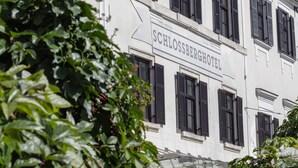 A white building with multiple windows and a sign that reads "SCHLOSSBERGHOTEL". - Schlossberghotel (Graz)
