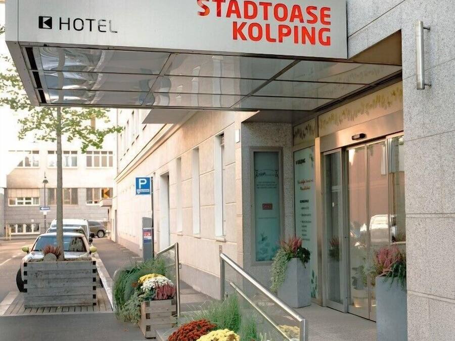 Een hotelentree met een bord waarop 'STADTOASE KOLPING HOTEL' staat.