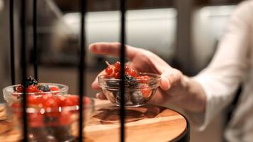 Eine Hand hält eine Glasbowl mit Beeren auf einem Holztisch.