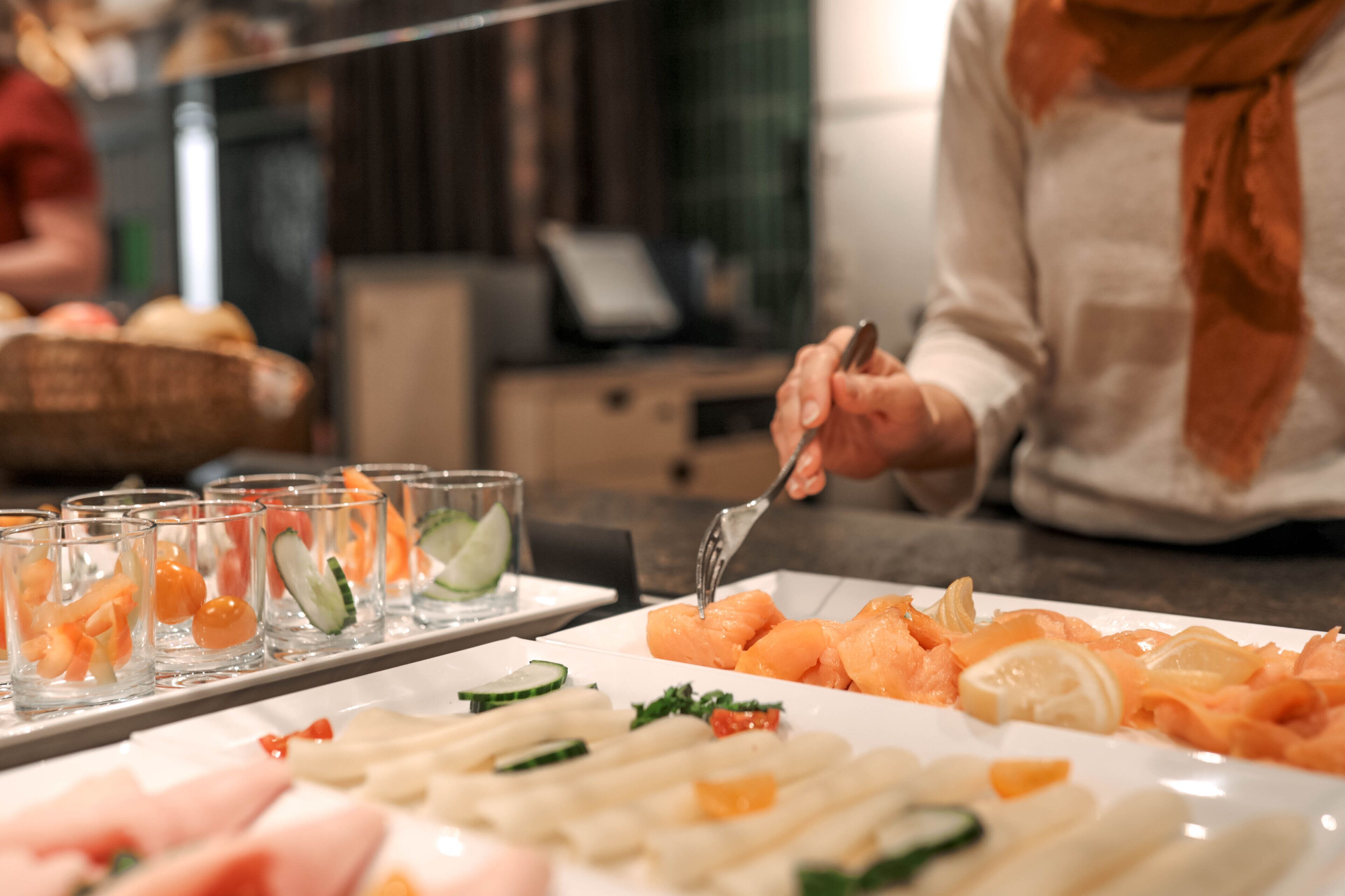 A buffet with various food items including salmon, vegetables, and fruits.