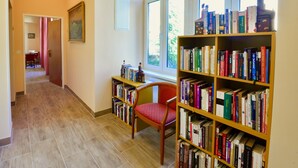 A library with bookshelves, a reading chair, and a painting on the wall. - Altwienerhof Boutique Hotel (Vienna)