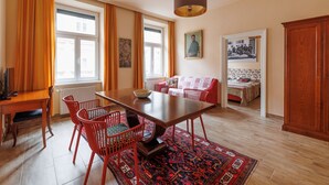 A dining area with a wooden table, red chairs, a rug, and a hanging light fixture. - Altwienerhof Boutique Hotel (Vienna)