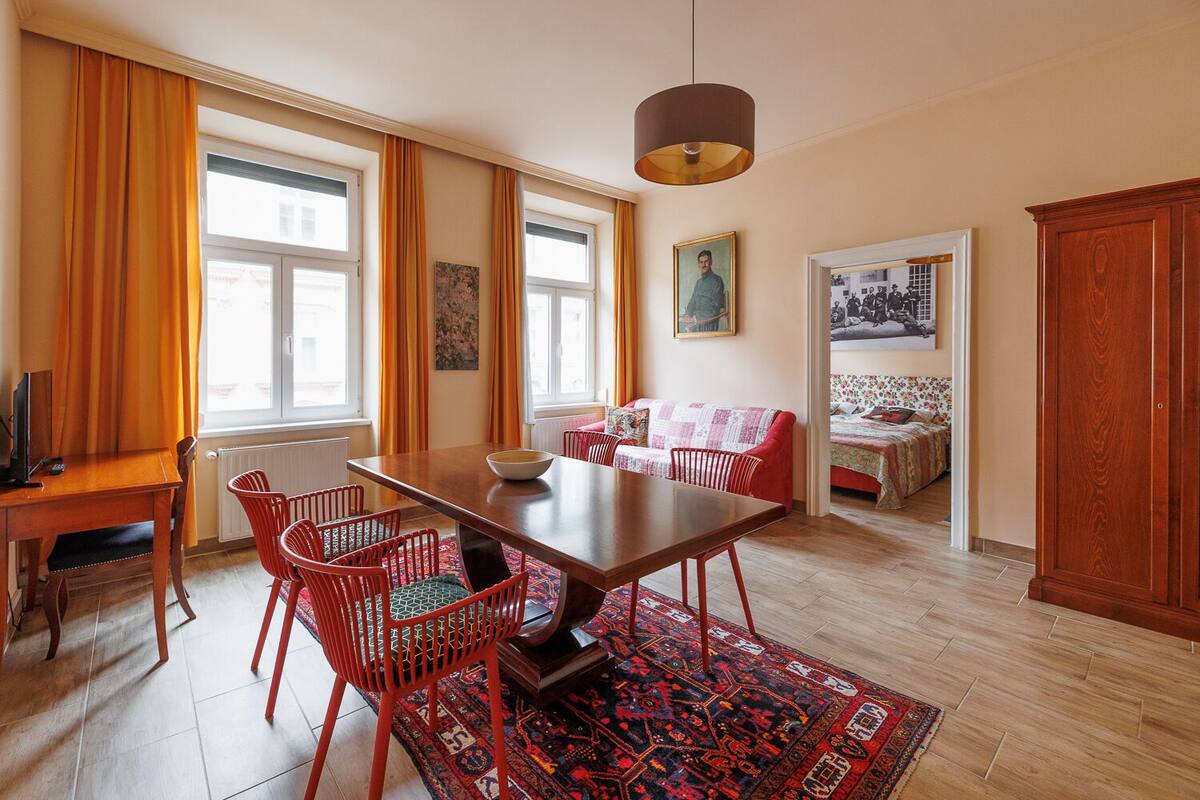 A dining area with a wooden table, red chairs, a rug, and a pendant light.