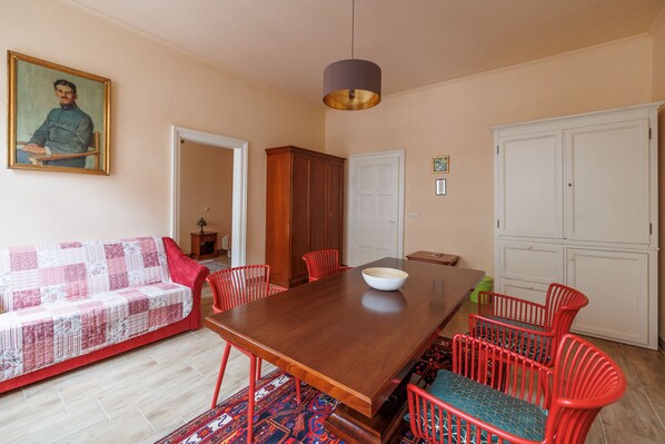 Un comedor con una mesa de madera, sillas rojas, un sofá rojo y un cuadro en la pared.