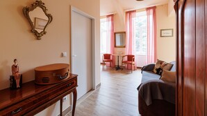 A room with a wooden dresser, a mirror, a table with chairs, and a sofa. - Altwienerhof Boutique Hotel (Vienna)