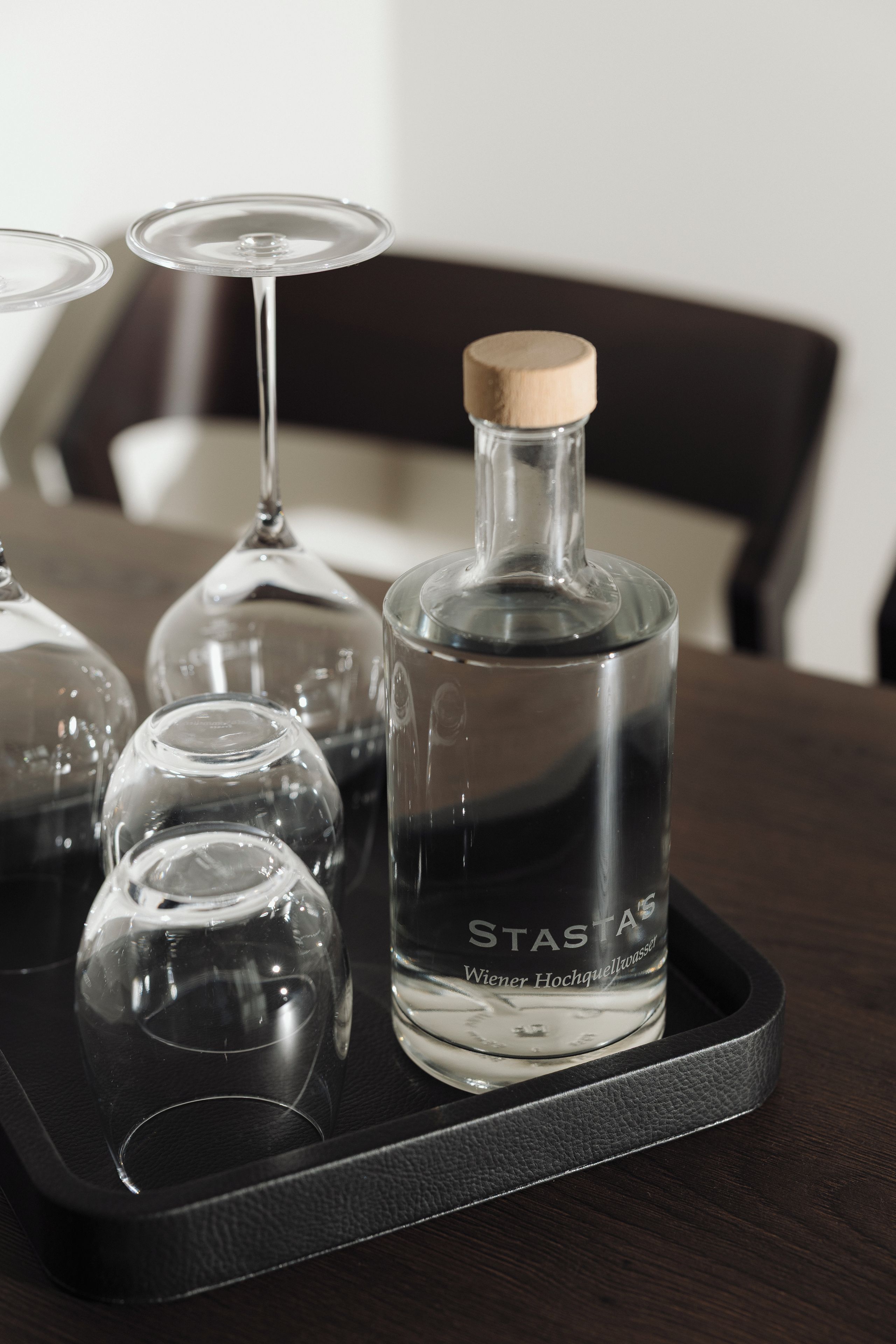 A tray with a bottle of StasA and several wine glasses on a table.