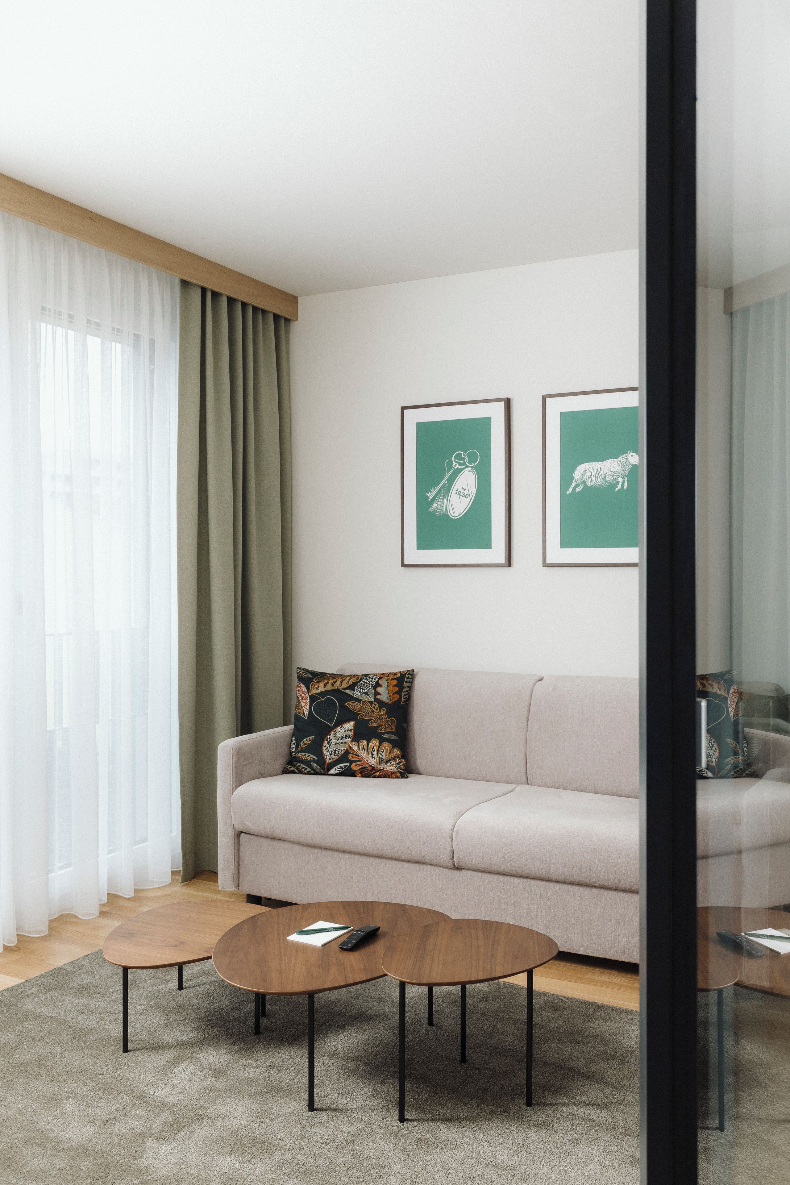 A modern living room with a sofa, two coffee tables, and framed artwork on the wall.