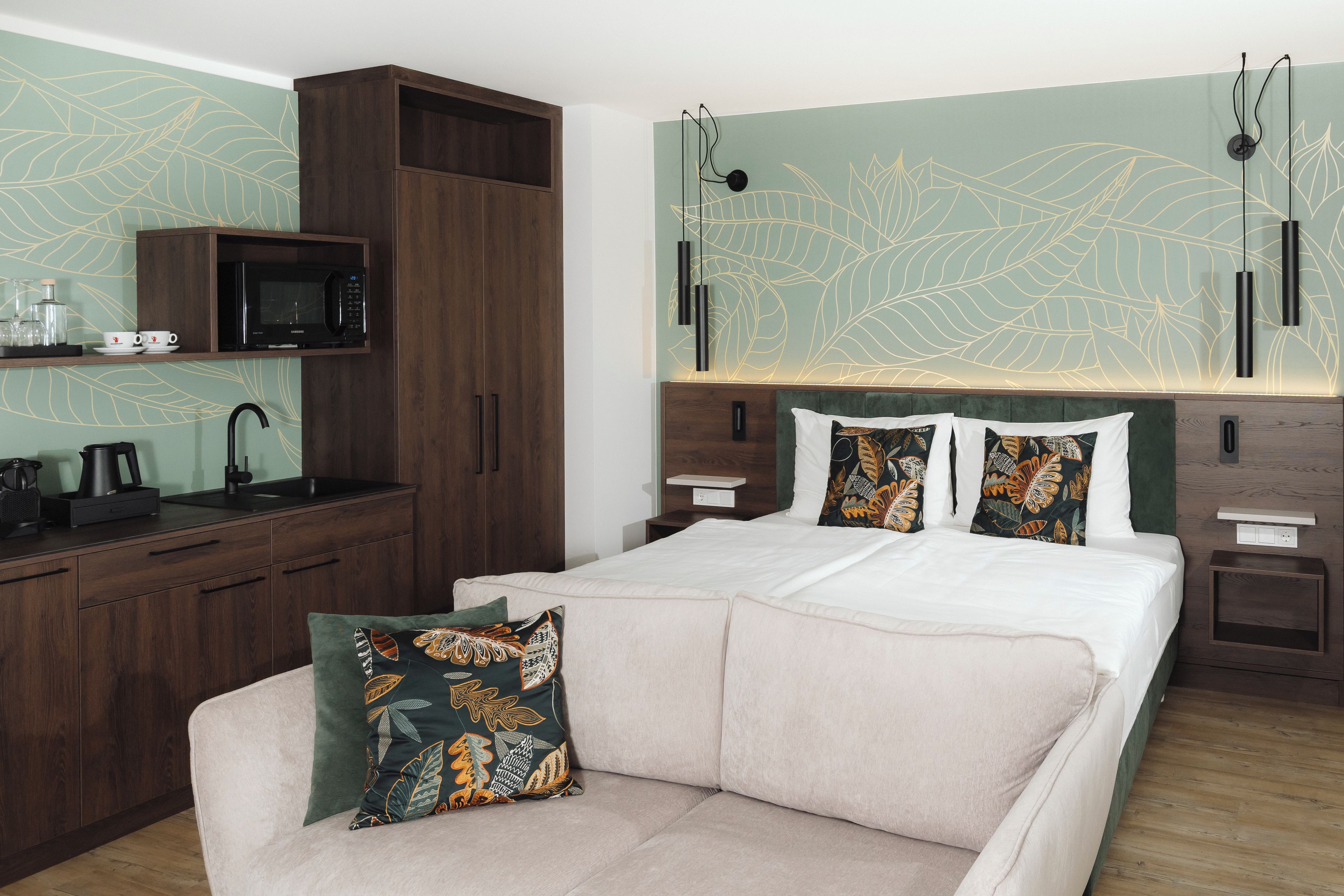 Ein modernes Schlafzimmer mit einem Bett, einer Couch, einer eingebauten Mikrowelle, einem Waschbecken und einer Wandleuchte.