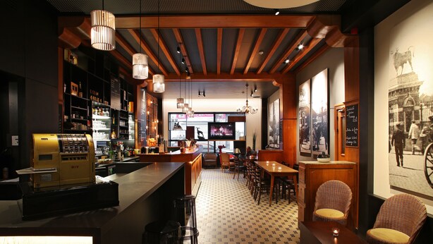 A bar area with a vintage espresso machine, wooden bar counter, and seating with wicker chairs. - Hôtel Van Belle (Brussels)