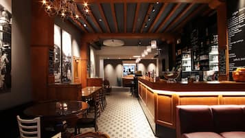Um restaurante com área de bar, teto de madeira e chão estampado.