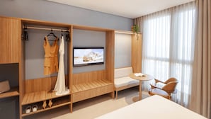 A modern hotel room with a TV, wooden wardrobe, seating area, and a window with curtains. - Intercity Florianópolis (Florianópolis)