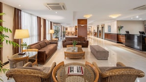 A spacious hotel lobby with a reception desk, sofas, and wicker furniture. - Intercity Florianópolis (Florianópolis)