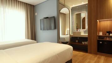 A hotel room with a bed, a TV, a mirror, a vanity with a sink, and a wardrobe.