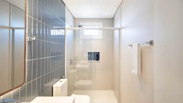 A modern bathroom with a glass shower enclosure, a toilet, and a sink.