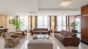 A modern hotel lobby with a seating area, a desk with computers, and large windows with curtains. - Intercity Florianópolis (Florianópolis)